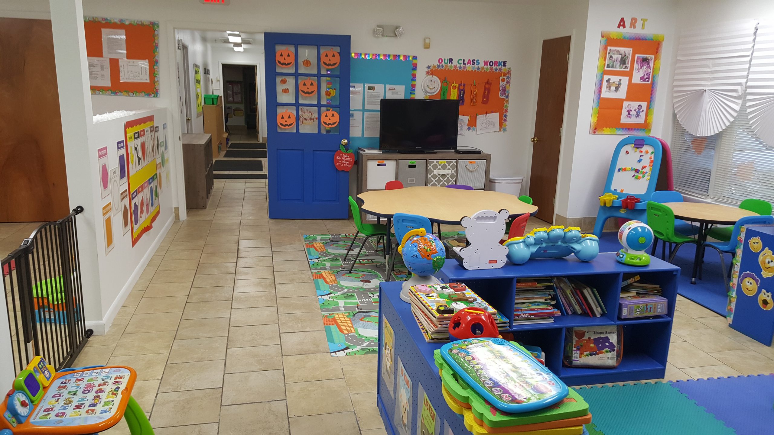 An organized preschool art and reading corner with activity tables, books, and developmental toys.
